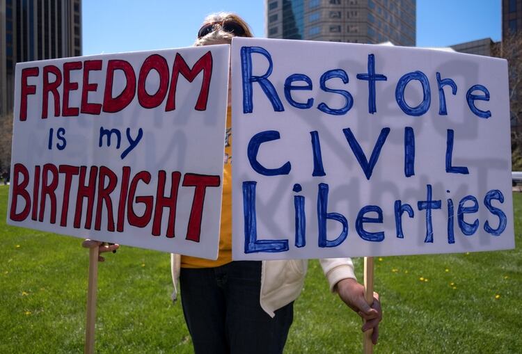 Una manifestante sostiene pancartas en una protesta contra las restricciones a la circulación en Ohio. REUTERS/Seth Herald