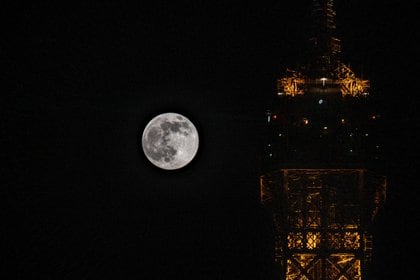 La luna llena se eleva sobre la Torre Eiffel en París, el 26 de abril de 2021
(Photo by Martin BUREAU / AFP)