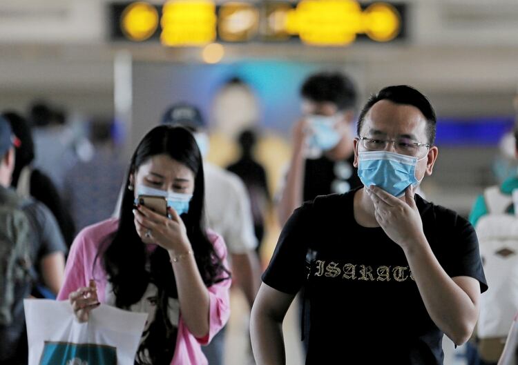 Pasajeros con máscaras al pasar frente a una máquina de escaneo que controla la temperatura de las personas tras el nuevo brote de coronavirus en China, en el aeropuerto internacional de Bandaranaike en Katunayake, Sri Lanka, el 24 de enero de 2020 (REUTERS/Dinuka Liyanawatte)