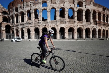 Un ciclista con mascarilla pasa por delante del Coliseo, en Roma. Foto: REUTERS/Guglielmo Mangiapane