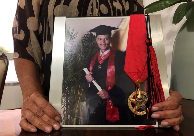 DOLOR FAMILIAR: La madre de Lira sostiene una foto de su hijo en su graduación universitaria (REUTERS/Angus Berwick)