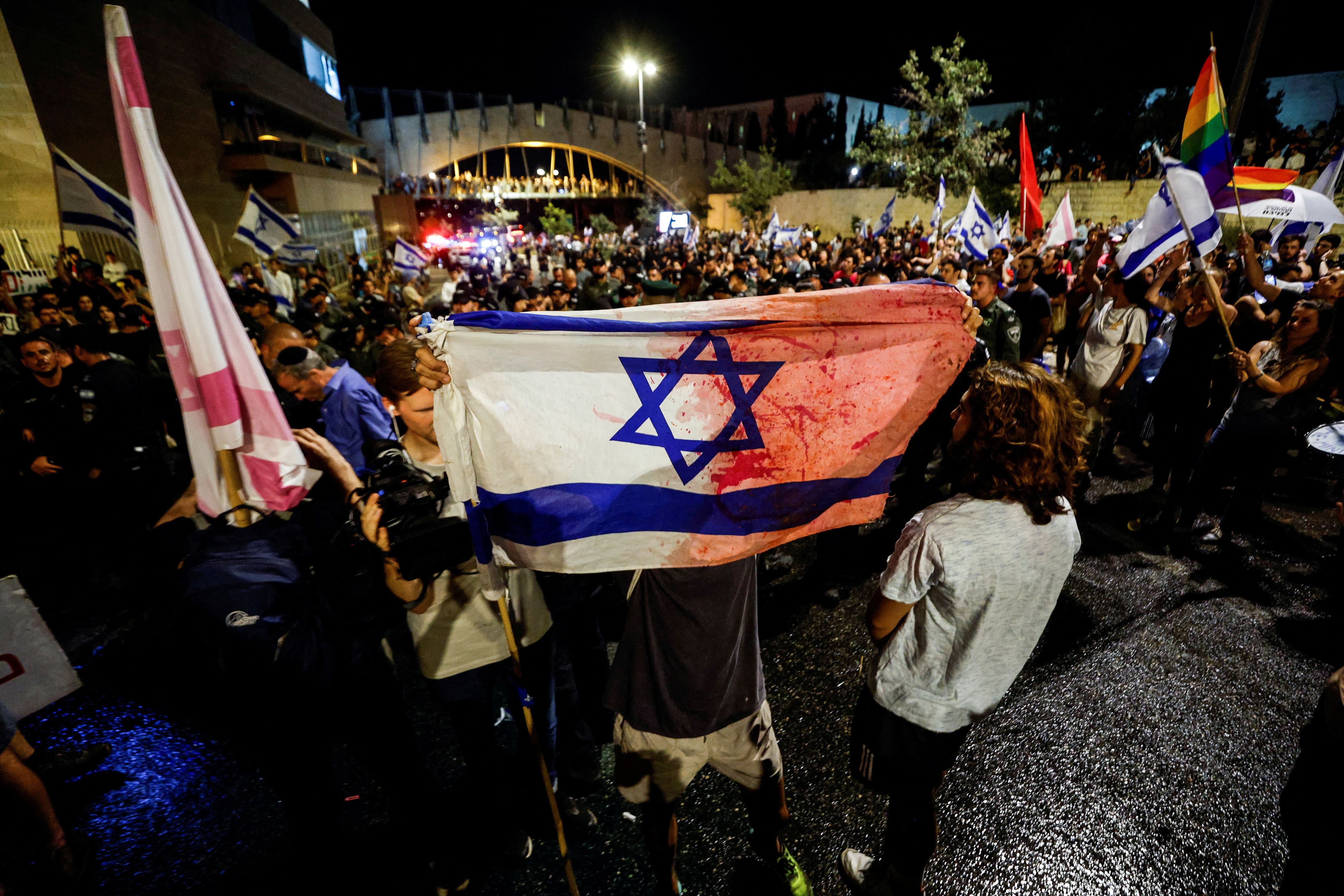 Una bandera israelí ensangrentada rescatada de un atentado fue flameada durante las manifestaciones contra la coalición de extrema derecha que gobierna el país. (REUTERS/Amir Cohen)