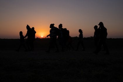 The sun rises as asylum-seeking migrants' families from Honduras and El Salvador walk towards the border wall after crossing the Rio Grande river into the United States from Mexico on a raft, in Penitas, Texas, U.S., March 26, 2021. REUTERS/Adrees Latif     TPX IMAGES OF THE DAY