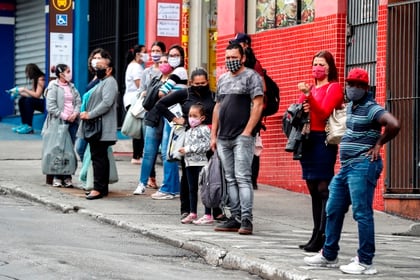 Personas con tapabocas esperan este jueves para tomar un bus de transporte público en Sao Paulo (Brasil). EFE/Sebastião Moreira
