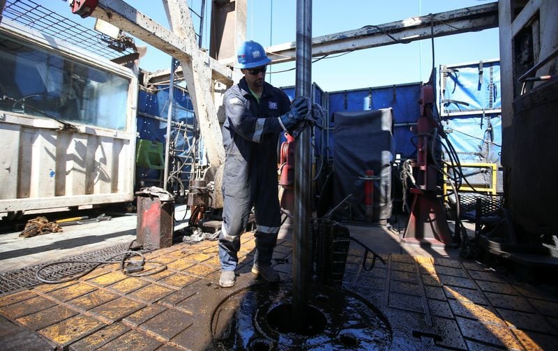 Un trabajador limpia una plataforma de perforación en la formación de petróleo y gas de Vaca Muerta, (Reuters)