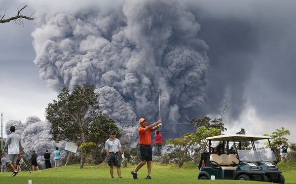 Personas juegan a golf mientras en el fondo se observa la erupciÃ³n del volcÃ¡n Kilauea el martes (Mario Tama/Getty Images/AFP)