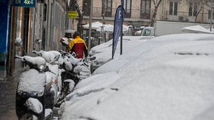 Un repartidor lleva cajas durante la nevada en Madrid, España, el viernes 8 de enero de 2021. La nieve cayó en la capital española por segundo día durante una ola de frío en la Península Ibérica. (Foto AP / Paul White)