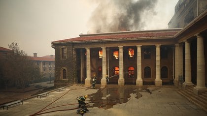 Firefighters battle flames as the library at the University of Cape Town burns after a bushfire broke out on the slopes of Table Mountain in Cape Town, South Africa, April 18, 2021. REUTERS/Mike Hutchings