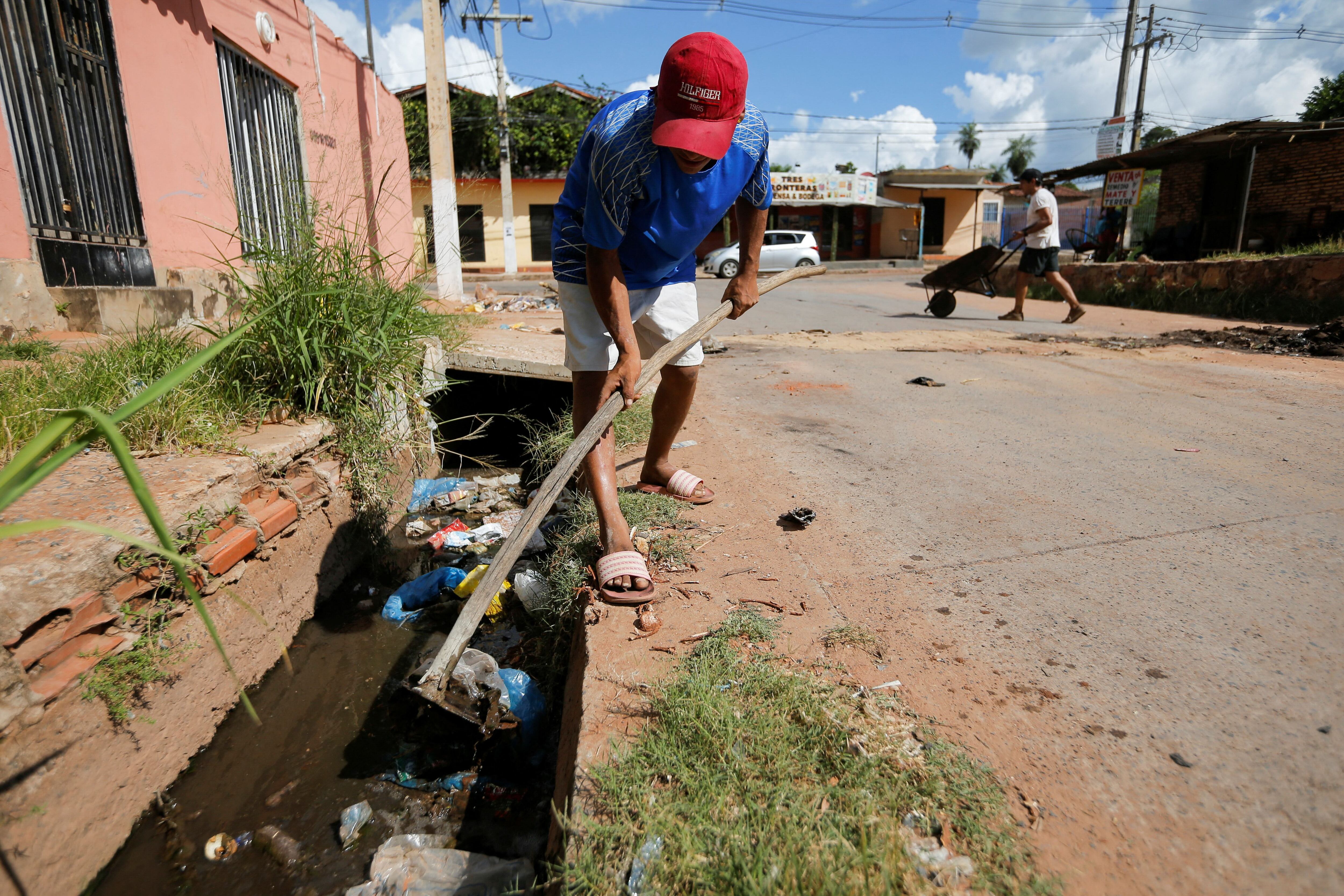 La gente limpia la basura del drenaje mientras las autoridades sanitarias están en alerta máxima debido a un aumento en los casos de dengue, una enfermedad transmitida por mosquitos, en Nemby, Paraguay, el 23 de enero de 2024. REUTERS/Cesar Olmedo