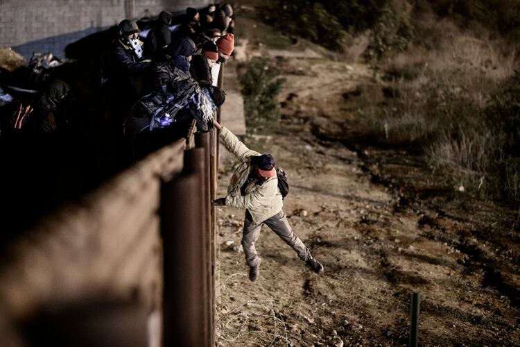 Los agentes de protección de la frontera de EE. UU. Envían a los migrantes a la parte mexicana de la valla fronteriza después de que subieron la valla para llegar a San Diego, California, desde Tijuana, México, el martes 1 de enero de 2019. (Foto AP / Daniel Ochoa de Olza)