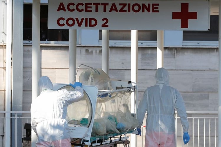 Personal médico con trajes de protección llevan una camilla de aislamiento en la Clínica Columbus, donde pacientes han sido trasladados desde el Hospital Spallanzani, en Roma (REUTERS/Remo Casilli)