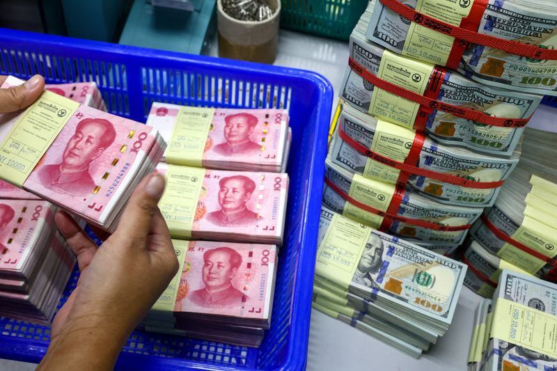 FOTO DE ARCHIVO. Un empleado bancario cuenta los billetes de renminbi (RMB) o yuan de China junto a los de dólar estadounidense. 26 de enero de 2023. REUTERS/Athit Perawongmetha