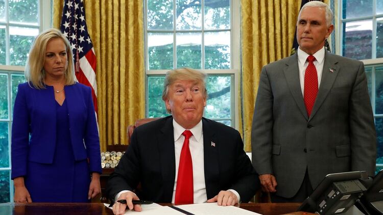 El presidente de EEUU, Donald Trump, firma una orden ejecutiva sobre política migratoria con la secretaria de Seguridad Nacional, Kirstjen Nielsen, y el vicepresidente, Mike Pence, a su lado en la Oficina Oval de la Casa Blanca en Washington, EEUU, el 20 de junio de 2018 (Reuters)