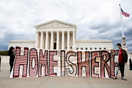 Dos personas sostienen un cartel que dice "Home is Here" fuera del Tribunal Supremo de Estados Unidos; como parte de una manifestación realizada por defensores de la inmigración y 'DREAMers' en Washington, DC, EE.UU., el 27 de abril de 2020. EFE/EPA/MICHAEL REYNOLDS/Archivo
