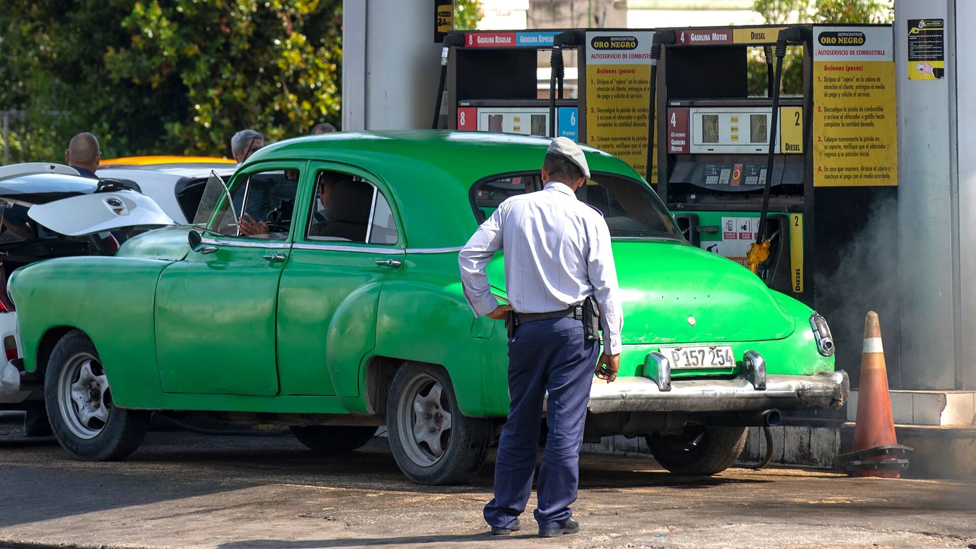 HAB101 La Habana (CUBA) 14/04/2023.- Un policía (de espaldas) observa a un coche antiguo en una gasolinera, hoy en La Habana (Cuba). El presidente de Cuba, Miguel Díaz-Canel, aseguró este viernes que el desabastecimiento de combustible en la isla se debe al "incumplimiento" de los países suministradores que también atraviesan una "situación energética compleja". "No es (por) insuficiencia, ni problemáticas de las instituciones, sino por incumplimiento de los países que nos suministran", precisó Díaz-Canel, en la primera declaración del Gobierno en las casi dos semanas de crisis de carburantes en el país. EFE/Yander Zamora