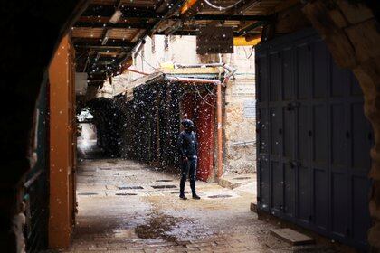 Un hombre observa cómo cae la nieve en un callejón de la Ciudad Vieja de Jerusalén el 17 de febrero de 2021. REUTERS / Ammar Awad