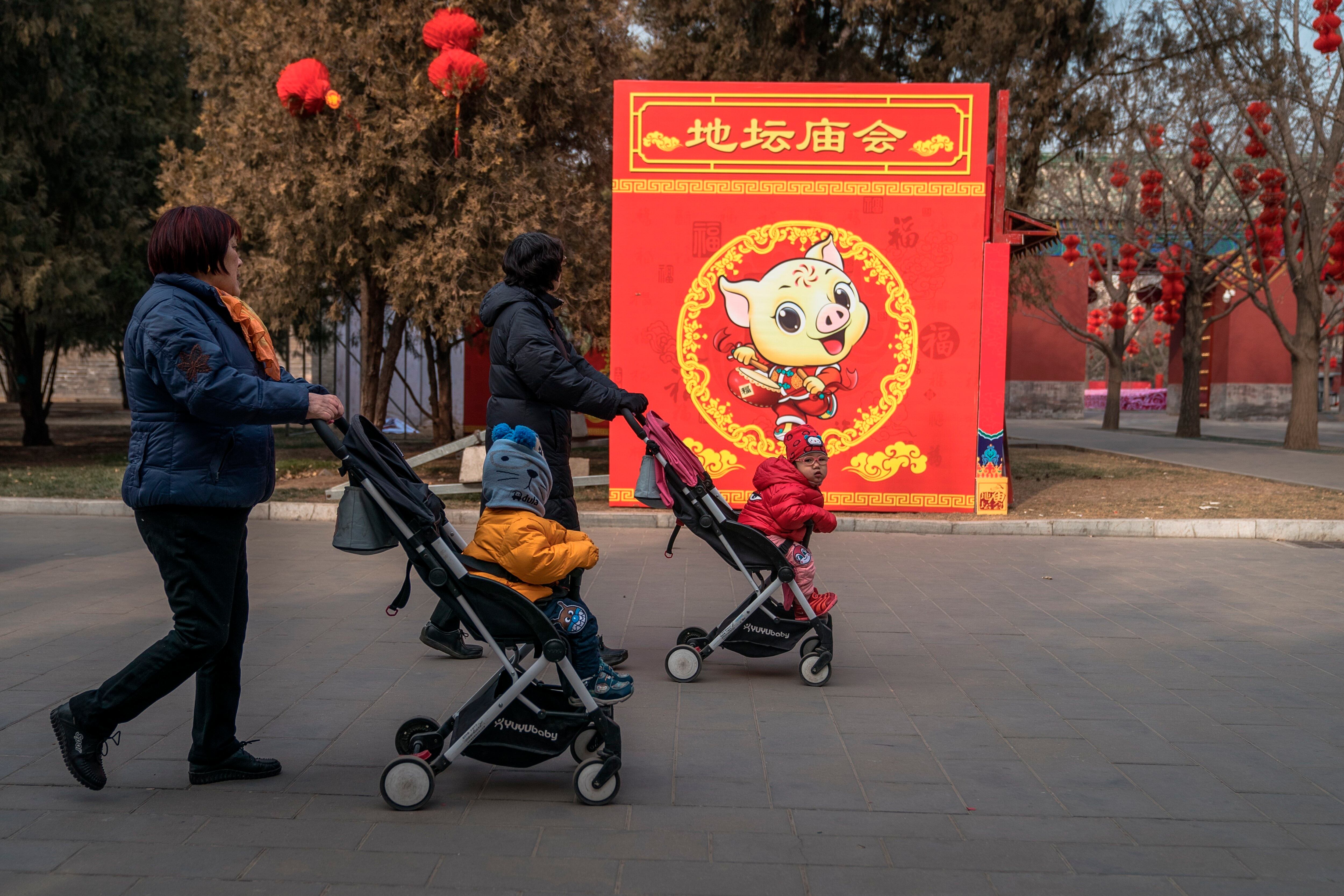 Dos mujeres con sus hijos por un parque de Beijing. EFE/Roman Pilipey/Archivo
