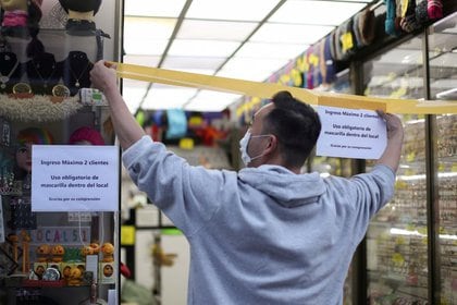 Un comerciante coloca una cinta para controlar el acceso a su tienda mientras se abre un área comercial durante el brote de coronavirus en Santiago, Chile. 17 de agosto de 2020 (REUTERS/Iván Alvarado)