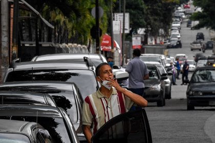 Un hombre fuma mientras espera en una fila para recargar combustible, afectado por la escasez, lo que frena la distribución de alimentos (AFP)