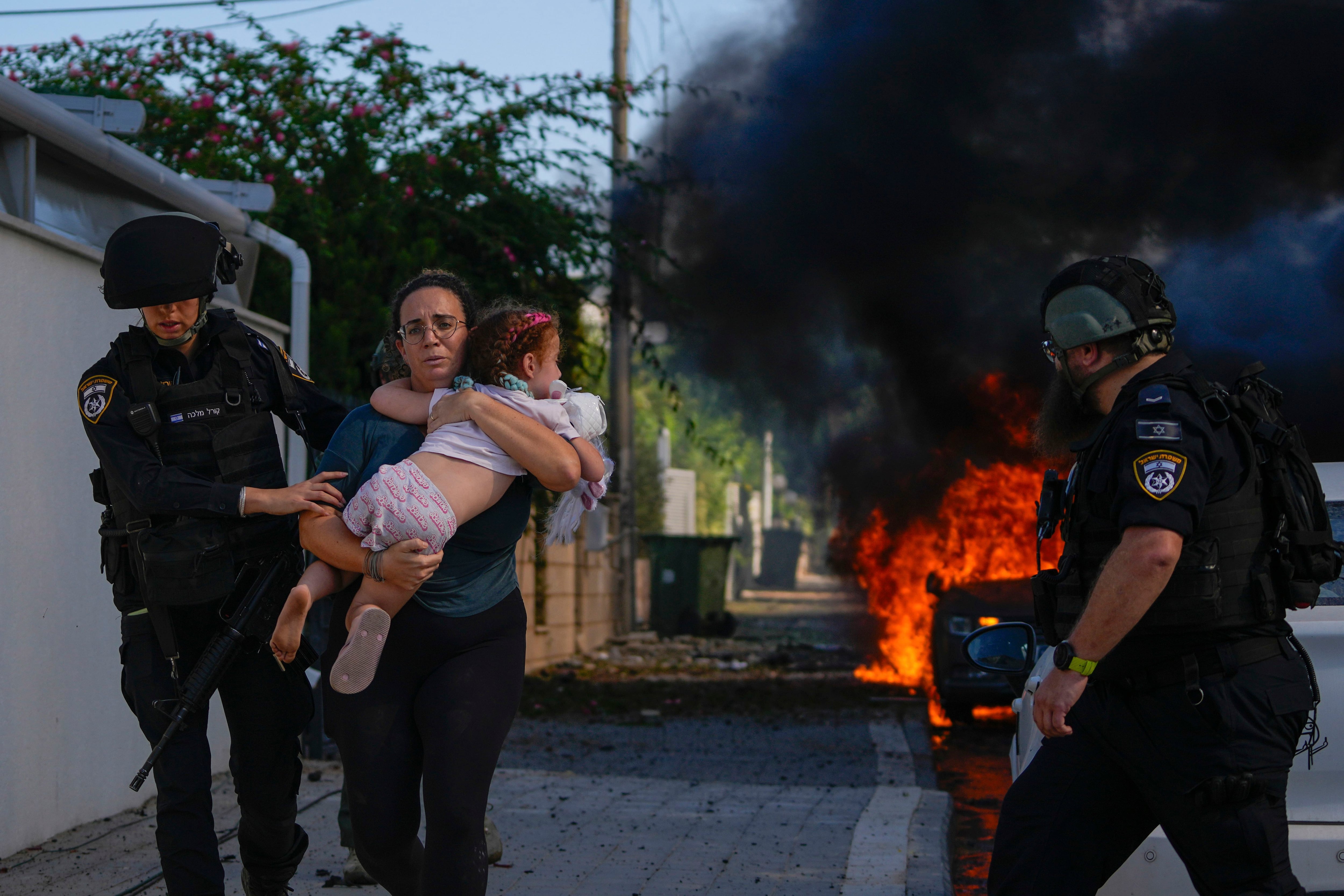 Agentes de policía evacuan a una mujer y un niño de un lugar alcanzado por un cohete disparado desde de Gaza, en Ashkelon, el sábado 7 de octubre de 2023 (Foto AP/Tsafrir Abayov, archivo)