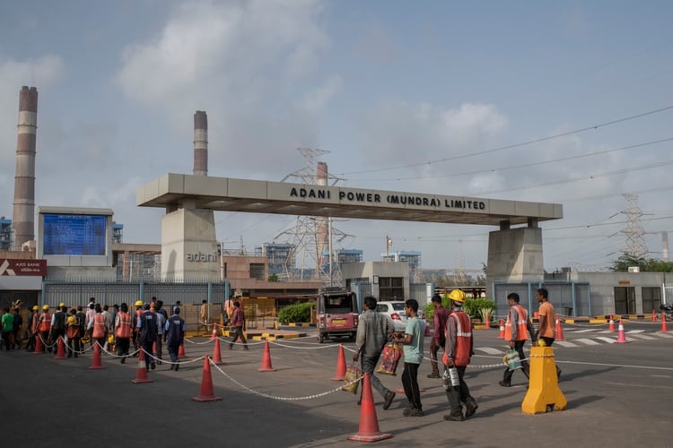 Un grupo de trabajadores llegaba a la central eléctrica de Mundra, en junio, para comenzar su turno. (Rebecca Conway/The New York Times)