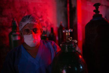 Un trabajador médico con un tanque de oxígeno en Manaos (Michael DANTAS / AFP)