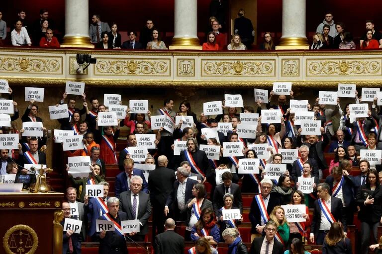     Miembros del parlamento de la izquierda sostienen pancartas tras el resultado negativo de la votación de la primera  