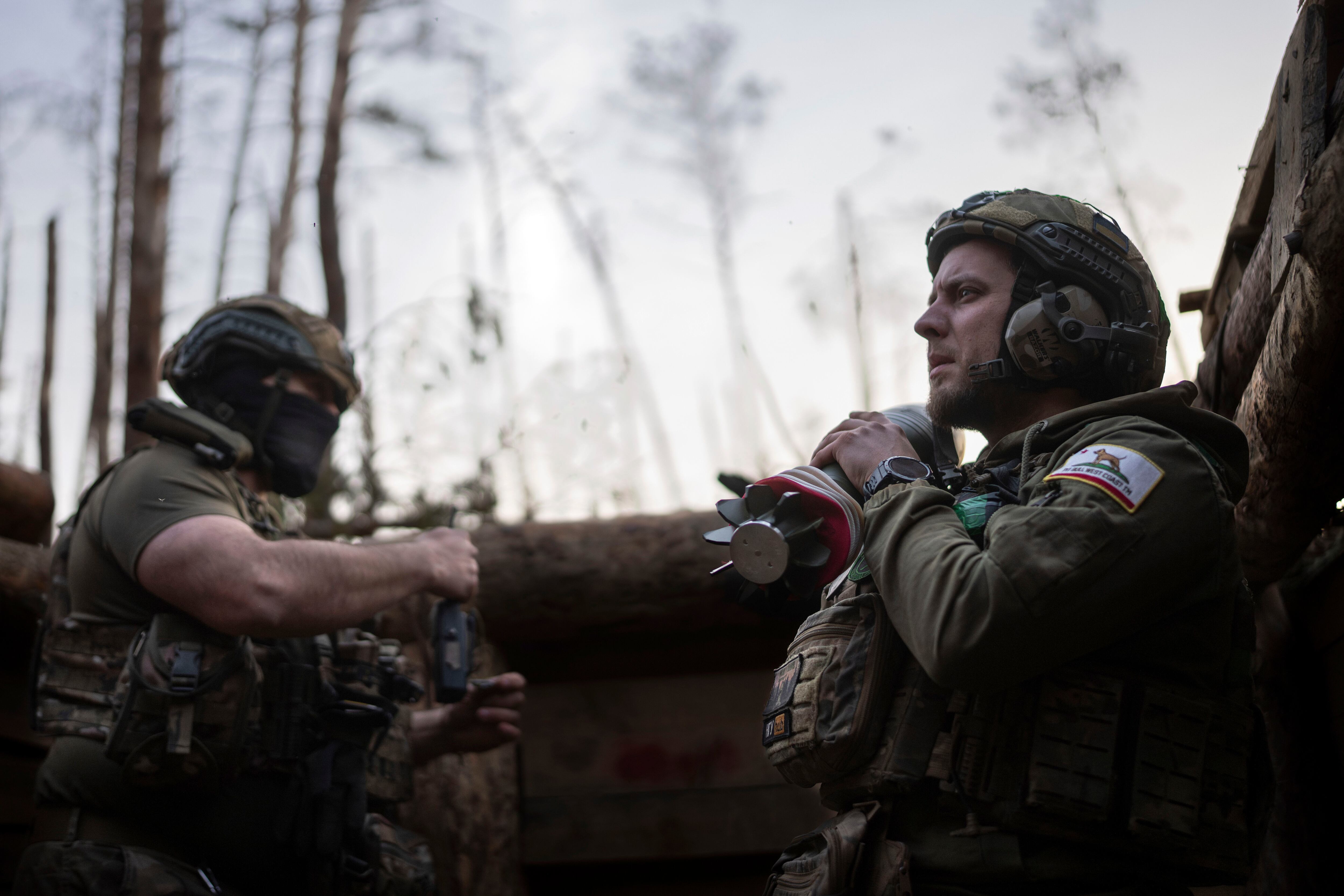 Un soldado ucraniano de la brigada Azov, conocido por su apodo Chaos, a la derecha, lleva un mortero mientras espera una orden de disparar en posiciones en torno a un kilómetro de distancia de las fuerzas rusas en el frente en dirección a Kreminna, en la región de Donetsk, Ucrania. (AP Foto/Alex Babenko)