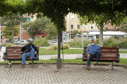 Dos hombres con mascarillas sentados en sendos bancos en el barrio de Carabanchel de Madrid, España, el 19 de septiembre de 2020 (REUTERS/Javier Barbancho)