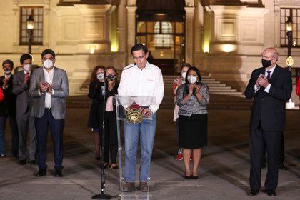 El presidente de Perú, Martín Vizcarra, baja la mirada mientras miembros de su gabinete le aplauden frente al palacio presidencia en Lima, después de que el Congreso aprobó destituirlo el lunes 9 de noviembre de 2020. (AP Foto/Martín Mejía)