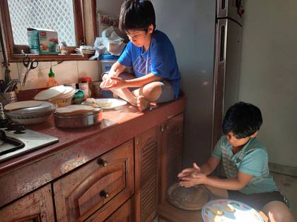 Uddhav Pratap, de 8 años (izquierda), y Advait Vallabh, de 9, ayudan en la cocina durante la cuarentena por el coronavirus. Estos hermanos creen que el encierro debería continuar durante un año. “No deberían reabrir hasta que queden cero casos”, dice el más pequeño, Uddhav Pratap. (Anil Sanweria vía AP)