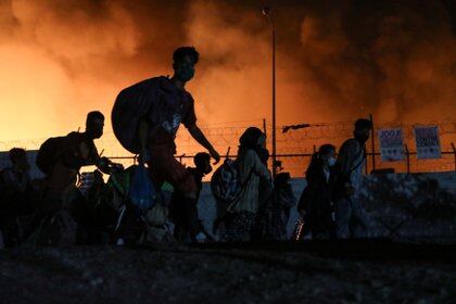 Refugiados y migrantes cargan con sus pertenencias mientras huyen de un incendio en el campamento de Moria, en la isla de Lesbos, Grecia. REUTERS/Elias Marcou