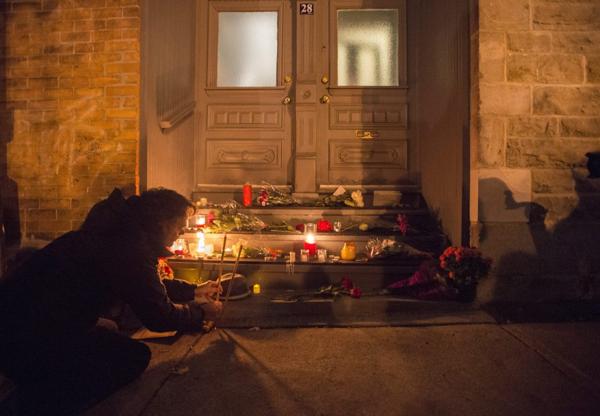 Un hombre enciende una vela en frente a la casa de Leonard Cohen, en Montreal. (The Canadian Press via AP)