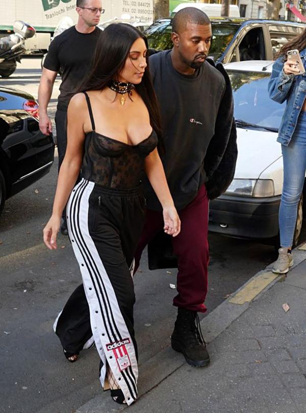 Kim Kardashian junto a Kayne West en las calles de Pars durante la semana de la moda. Pantalones Adidas con un body de encaje y transparencias