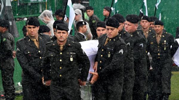 Bajo una lluvia torrencial, los soldados llevaron los cuerpos de los futbolistas al campo de juego (AFP)