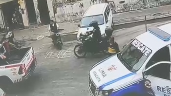 Camionetas de rescate, motocicletas y transeúntes en una calle urbana captados desde una cámara de seguridad
