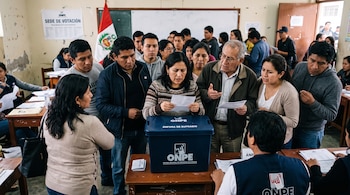 Personas reunidas alrededor de una mesa con una caja azul con la sigla ONPE, la bandera peruana al fondo y un cartel de centro de votación.