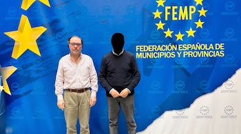 Dos hombres de pie frente a un panel azul con el texto Federación Española de Municipios y Provincias, uno de ellos con el rostro siluetado.