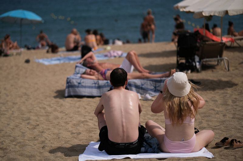Turistas disfrutan del mar Mediterráneo en la playa de la Barceloneta en Barcelona. (REUTERS/Nacho Doce)