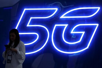 FOTO DE ARCHIVO: Una mujer mira su teléfono móvil junto a una señal luminosa de 5G en el Mobile World Congress en Barcelona, España, el 25 de febrero de 2019. REUTERS/Sergio Pérez