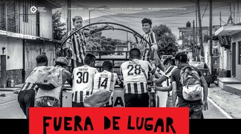 Fotografía en blanco y negro de siete hombres jóvenes en la parte trasera de un vehículo. Visten camisetas de fútbol. Fondo urbano con texto en rojo