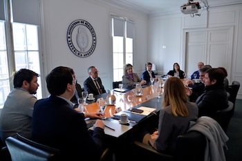 Personas sentadas alrededor de una mesa de reuniones frente al emblema del Ministerio de Seguridad de Argentina colgado en la pared