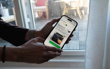 Primer plano de manos sosteniendo un iPhone 14 Pro con pantalla encendida mostrando una guía sobre cómo enchufar un aire acondicionado a una estación de energía