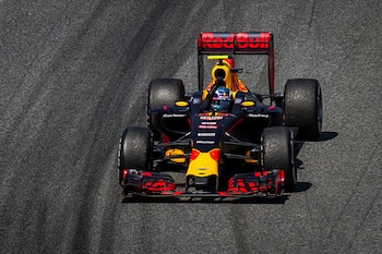Vista superior de un coche de Fórmula 1 Red Bull negro, rojo y amarillo con el alerón trasero visible, circulando por una pista de asfalto oscuro