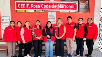 Grupo de nueve personas, siete mujeres y dos hombres, posa frente a la fachada de un edificio rojo con un cartel que dice 'CEDIF. Rosa Coda de Martorell' y una placa con texto