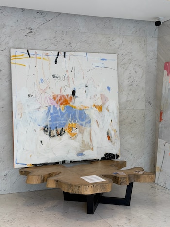 Un cuadro abstracto apoyado detrás de una mesa de madera con patas metálicas negras sobre un suelo de mármol