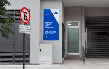 Fachada de edificio con cartel azul de Ministerio Público de la Acusación, Unidad Fiscal de Violencia de Género, y señal de prohibido estacionar para Fiscalía