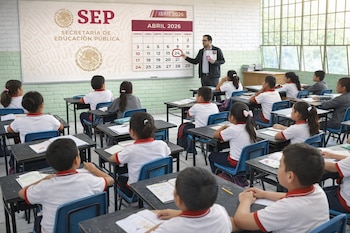Un profesor señala el 24 de abril de 2026 en un calendario de la SEP en la pizarra. Una docena de estudiantes de primaria están sentados en sus pupitres.