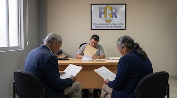 Dos adultos mayores y un funcionario en una oficina con un escritorio. Un cartel con el texto 'Procuraduría General de la República de El Salvador' está visible.