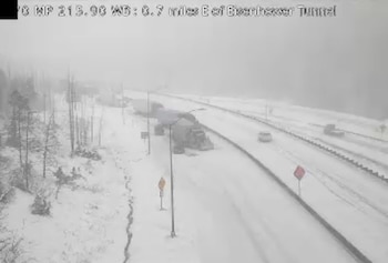 Vista aérea de la Interestatal 70 cubierta de nieve cerca del Túnel Eisenhower-Johnson con varios vehículos y árboles. La visibilidad es baja debido a la nevada